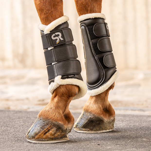 black dressage leather boots from leather and fur inside with elastic velcro closures on horse leg