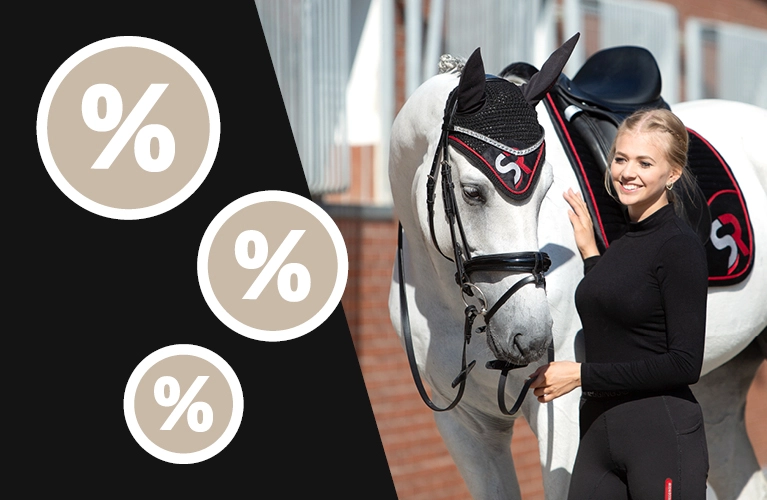 Sale Eine Reiterin steht neben einem Pferd mit schwarz roter Schabracke und passender Fliegenhaube mit SR Logo im Hintergrund ist ein Stall