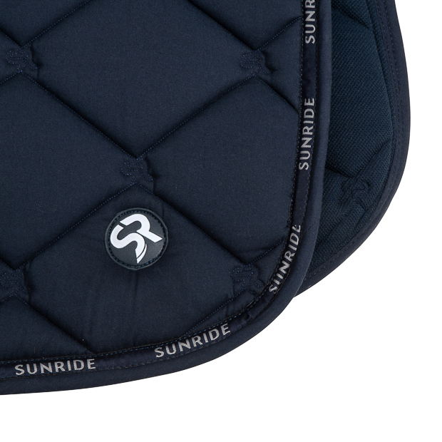 detailed view of sr quiting and logo on blue wellington line jumping saddle pad with breathable air mesh spine by sunride