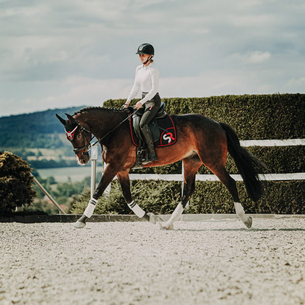 breathable dressage saddle pad red and black exclusive line with fur on withers under saddle on a horse in full sunride set