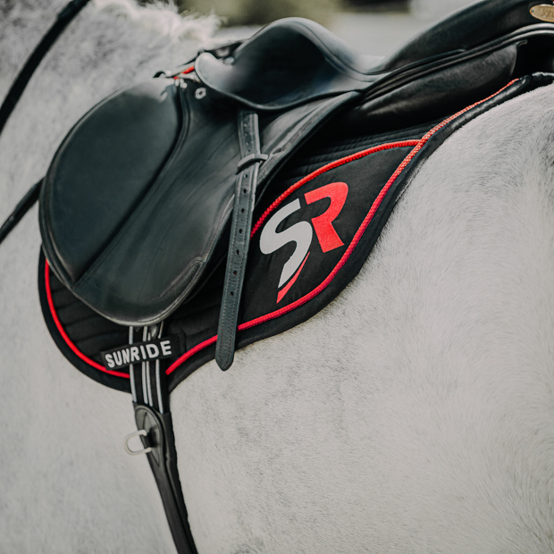 black red sr line jumping saddle pad with breathable air mesh spine by sunride under a saddle on a horse