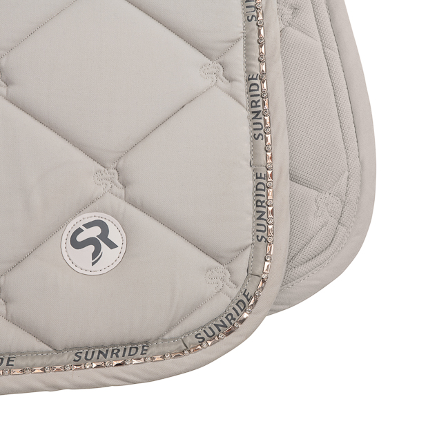 logo and stones of dressage saddle pad wellington beige with gemstones, breathable spine and padded withers breathable dressage saddle pad wellington beige with detailed view of gemstones and fur on withers