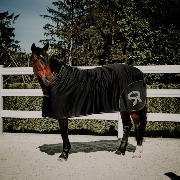 black boston cooler rug made of softshell and fleece with reflecting sr logo by sunride on a horse in paddock