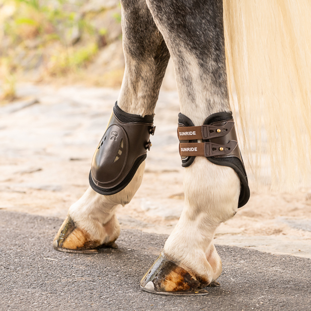  brown high leather fetlock boots with protection layer and elastic closure straps by sunride on a horse leg