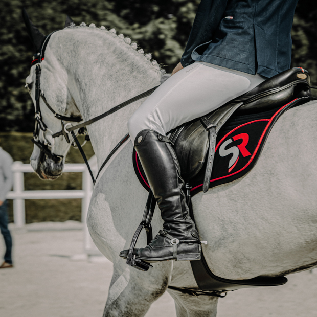 black red sr line jumping saddle pad with breathable air mesh spine by sunride under a saddle on a horse with rider