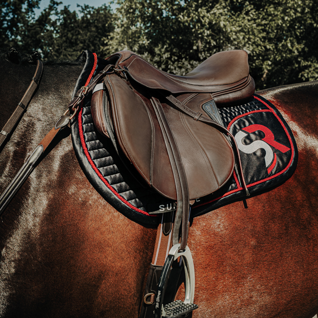 black red sr line jumping saddle pad with breathable air mesh spine by sunride under a saddle on a horse