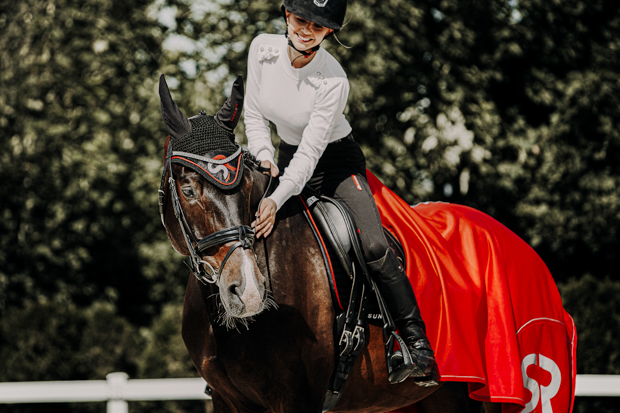 red set of earnet and boston cooler rug made of softshell and fleece with reflecting sr logo by sunride on a horse with rider