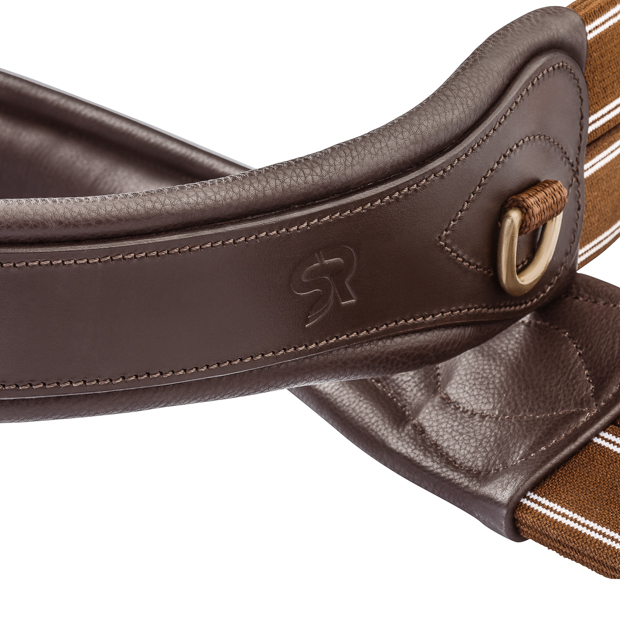 detailed view of d-ring of elastic brown leather saddle girth soho with golden mounting by sunride