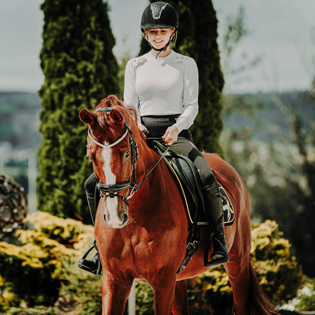 rider and horse with aspen swedish leather bridle black including reins in sr line equipment swedish leather bridle aspen with glossy nose band and matching gem stones in black with silver mounting including reins and sr line gold black equipment on a horse with rider
